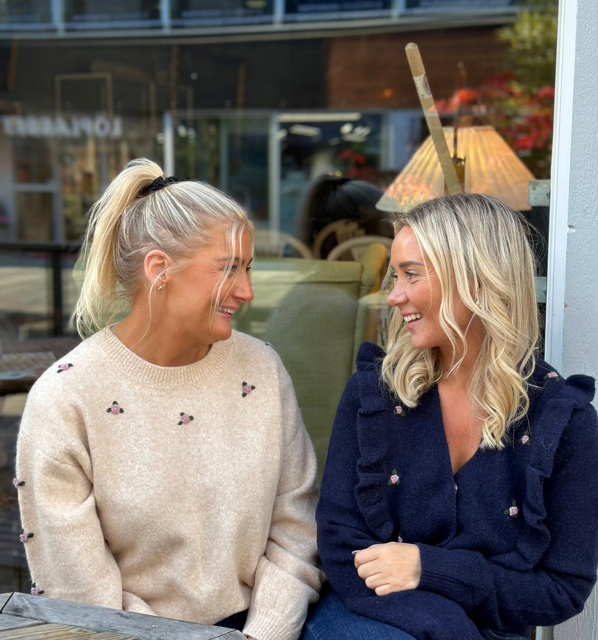 Bilde av to ansatte fra Klara Tønsberg som sitter og smiler til hverandre