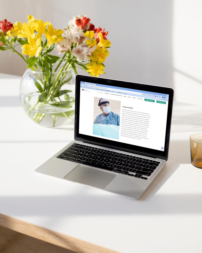 Bilde av en PC som viser hjemmesiden til KlinikkHaukeland med en blomst i bakgrunnen