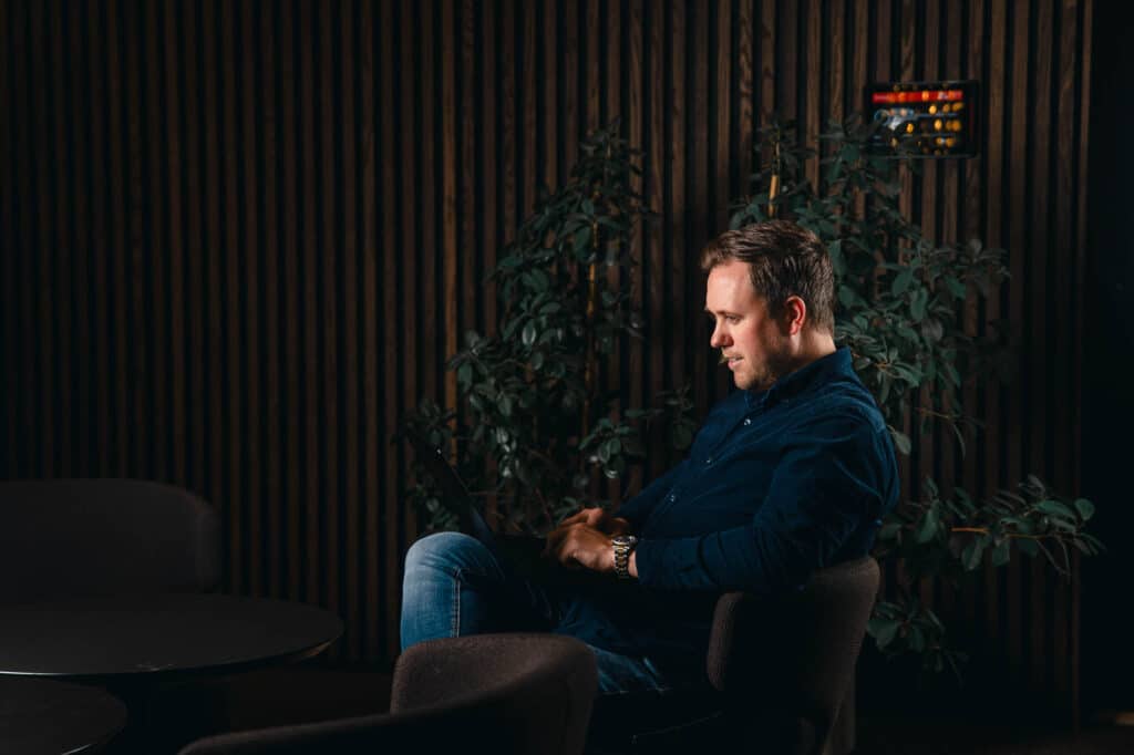 Bilde av Benjamin Lind Enger som sitter og jobber på en datamaskin på mørk bakgrunn